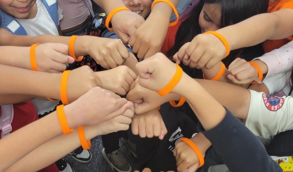 children standing in a group with their fists all bumping in the middle.
