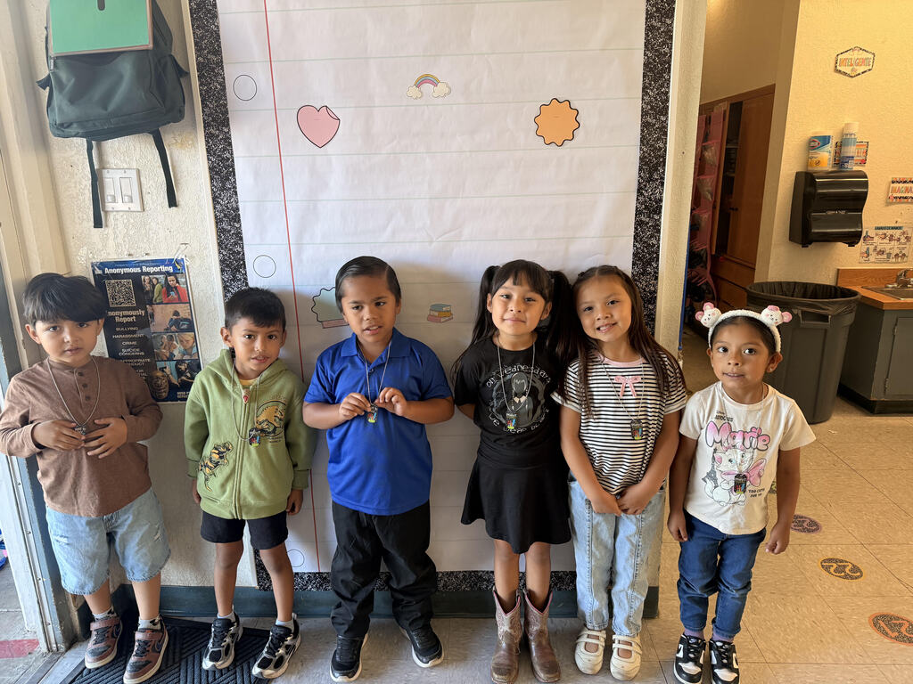 A collection of photos celebrating Joshua Circle Elementary students who earned Perfect Attendance Brag Tags. Students of various grade levels smile and proudly hold or wear their colorful brag tags on necklaces. The photos were taken around campus, including classrooms and outside the school. One large group photo shows several dozen students together, while the other photos feature smaller groups of students displaying their awards.