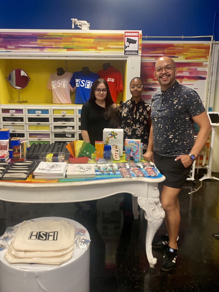 HSFI Business teacher Dennis Jimenez along with HSFI Senior volunteers Liliana Sanchez and Niseiry Elliz-Casildo setting up shop