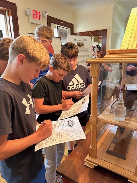 image shows junior high school students taking notes at each station they visit on their tour of the pow/mia museum.