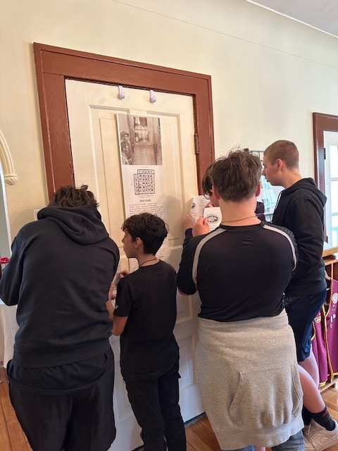 image shows junior high school students taking notes at each station they visit on their tour of the pow/mia museum.