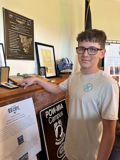 image shows a junior high school student pointing at a war medal inside the pow/mia museum at Jefferson Barracks.