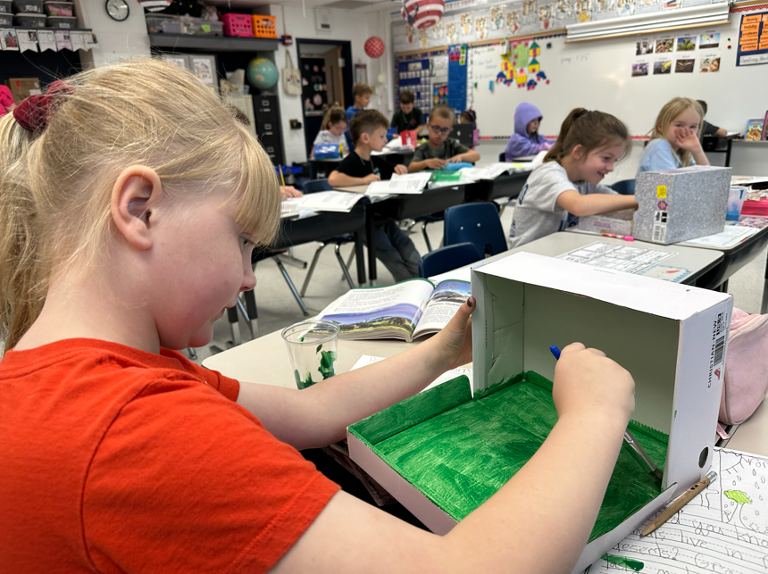 Student concentrates on painting her class project. Building animal habitats.