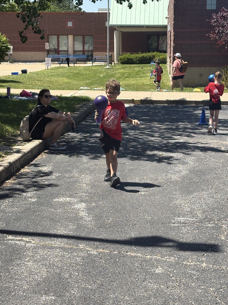 image is of a student running with a ball during field day at the primary