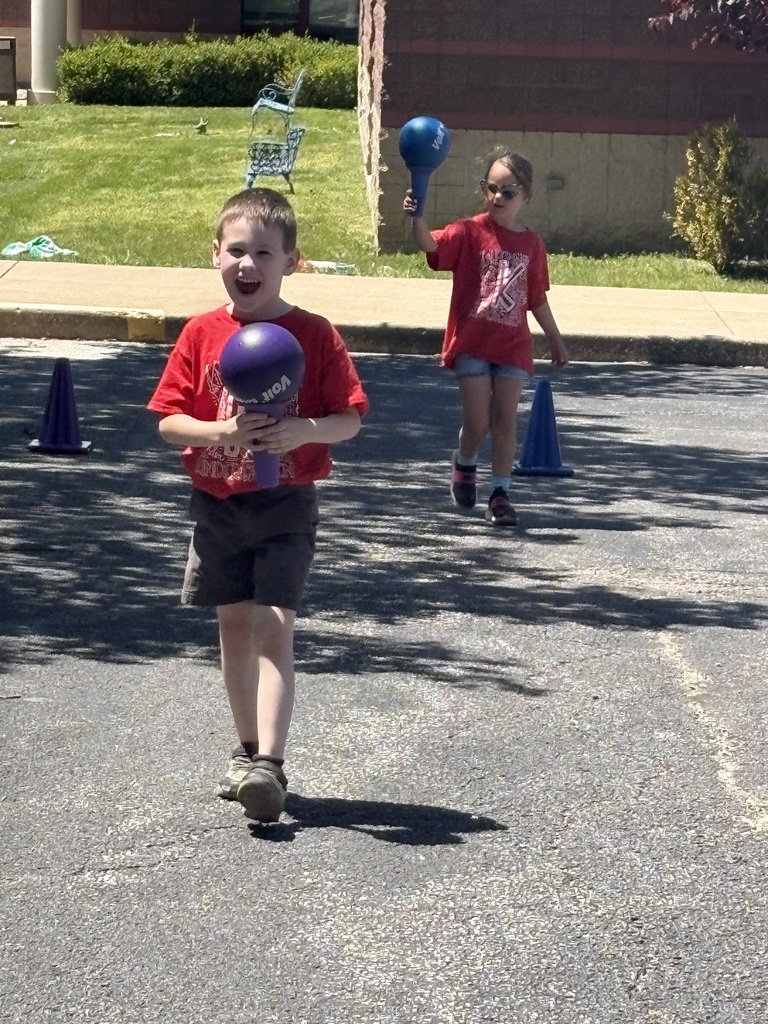 image is of two students running with a ball during field day at the primary
