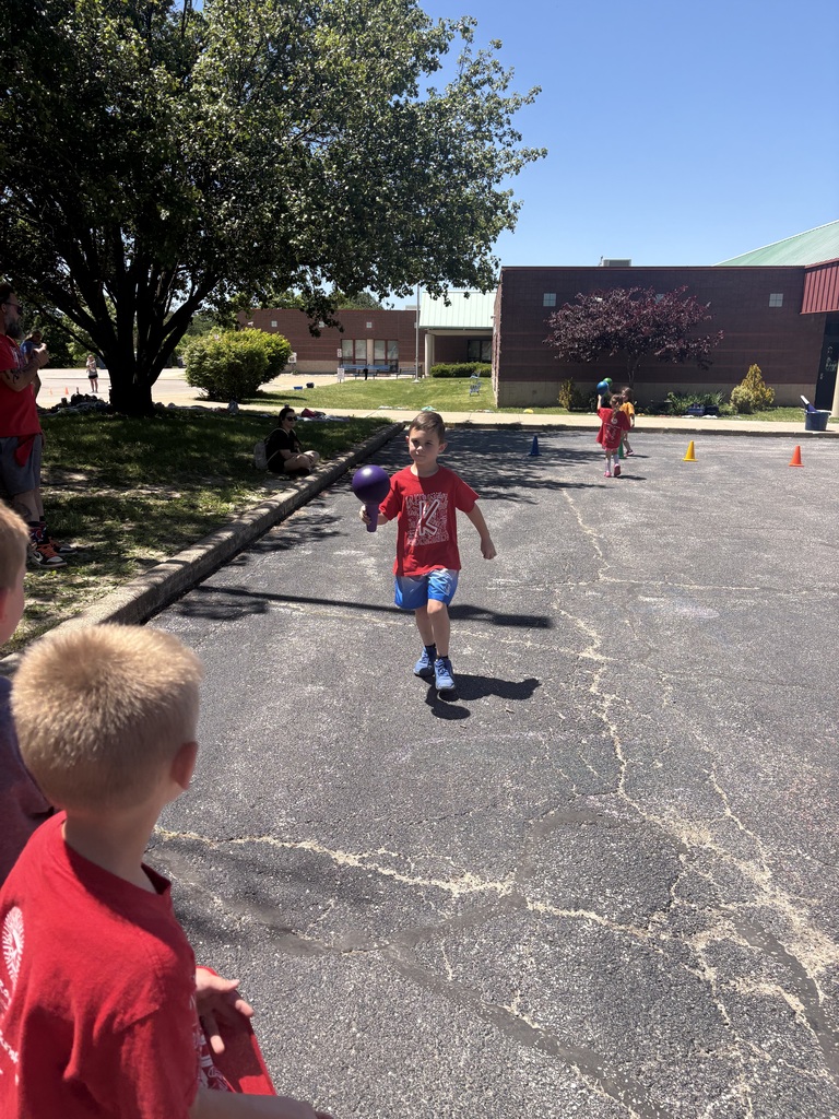 image is of a student running with a ball during field day at the primary