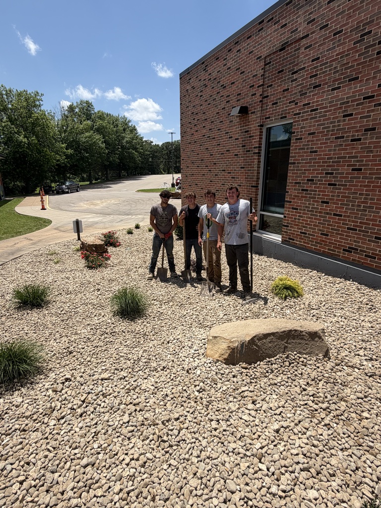 Mower Crew standing with several new plants, "planted" outside of the front entrance to Hillsboro Elementary School