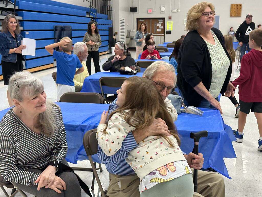 image is of students hugging their grandparents during grandparents day at the intermediate school