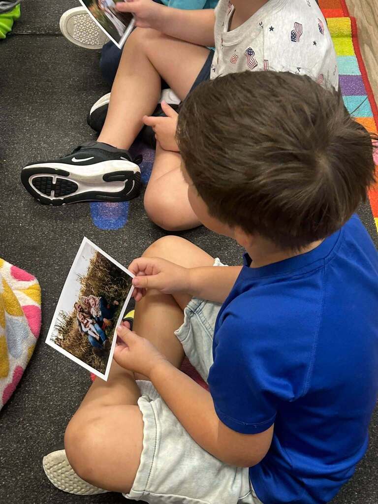 child sitting on the ground holing a picture. 