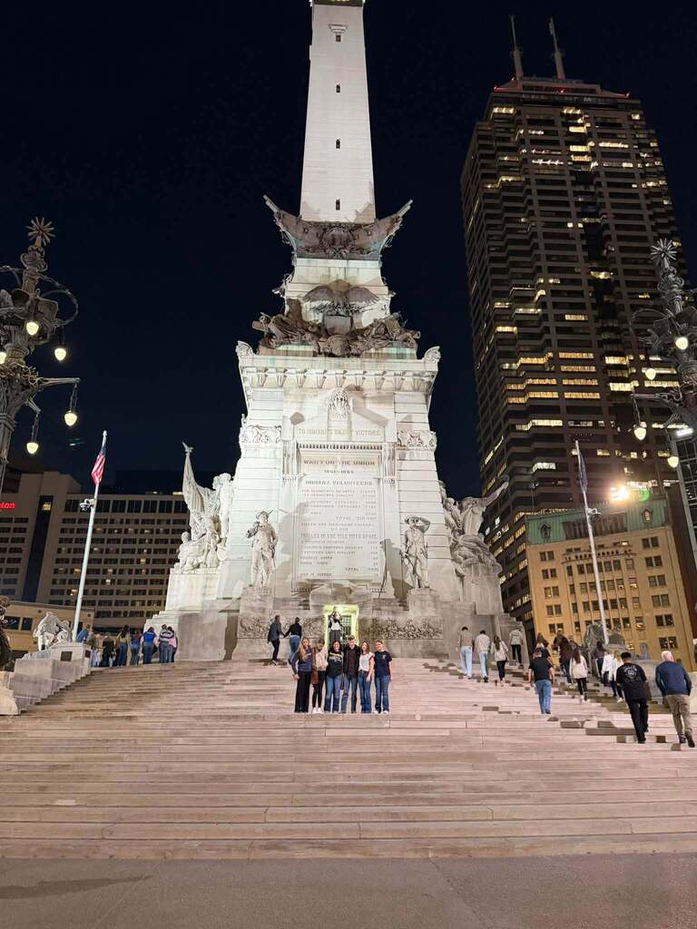 students standing on steps in front of a tall structure