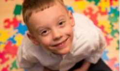 seated boy look up and puzzle pieces on the floor around him
