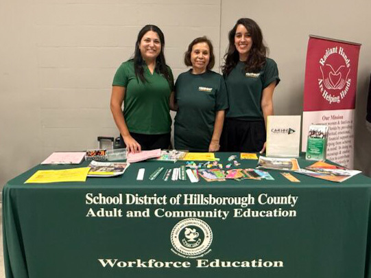Dima Walters and her colleagues at the CARIBE Refugee Program with Hillsborough County Adult and Community Education stand. Photo by Leah Burdick