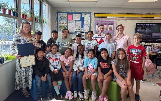 A group of smiling Reddick Elementary students with Kimberly Cooke who received an award/