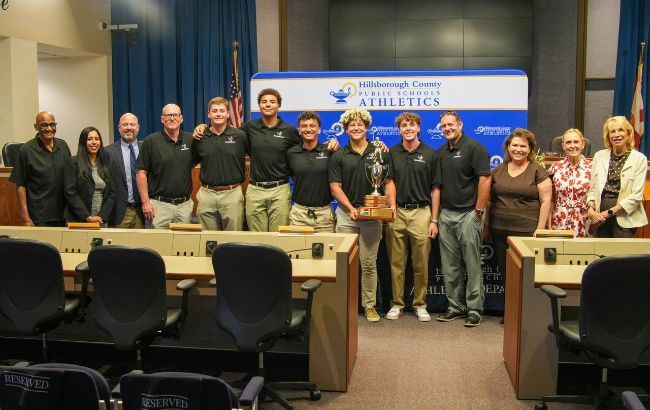 Group of students smiling receiving an athletic awards from the HCPS Board members.