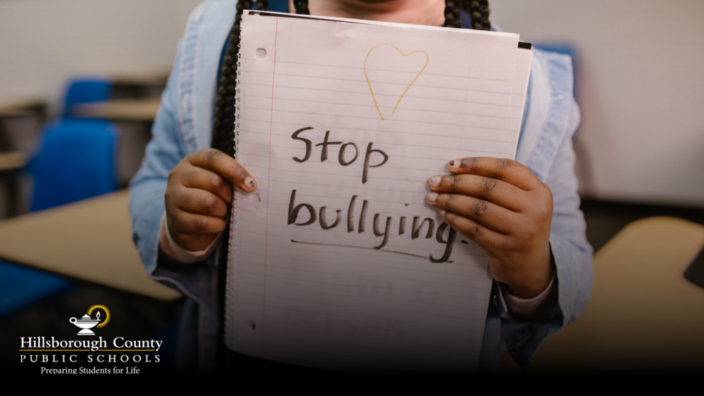 A girl holding a notebook with a text writting Stop Bullying
