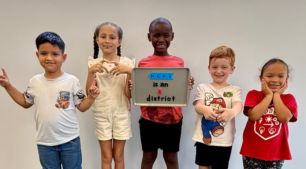 Elementary students smiling and holding up a sign that reads "HCPS is an A district"