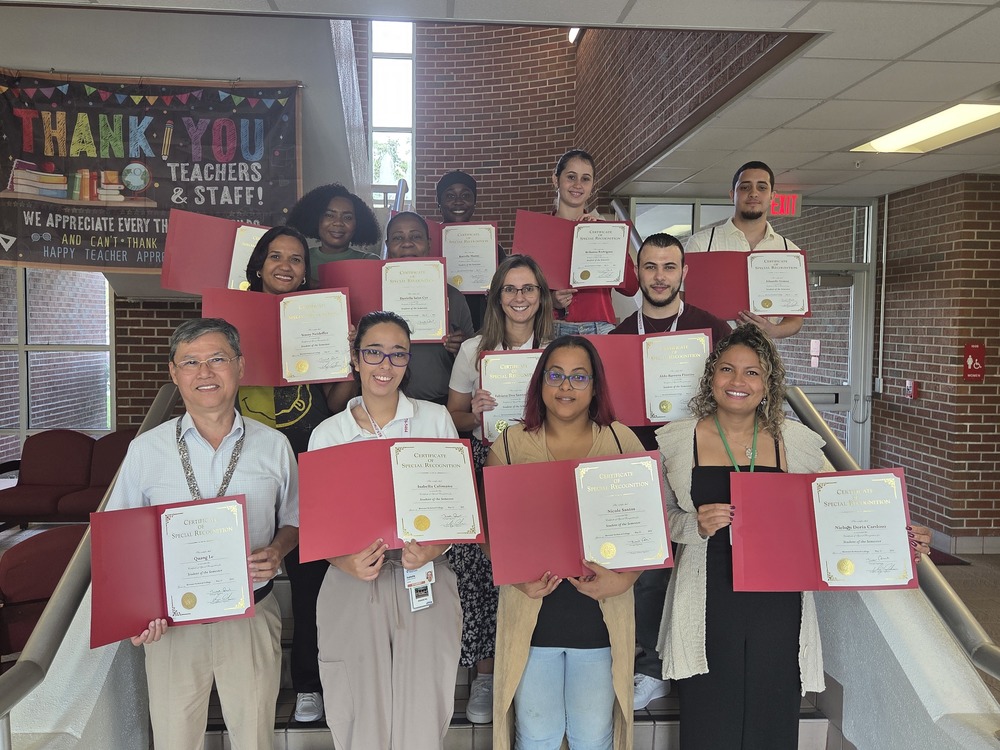 students holding certificates standing on stairs