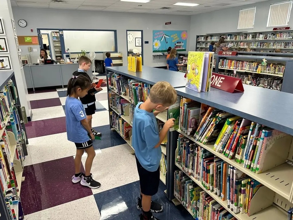 Class holding up the books they checked out of the library. 