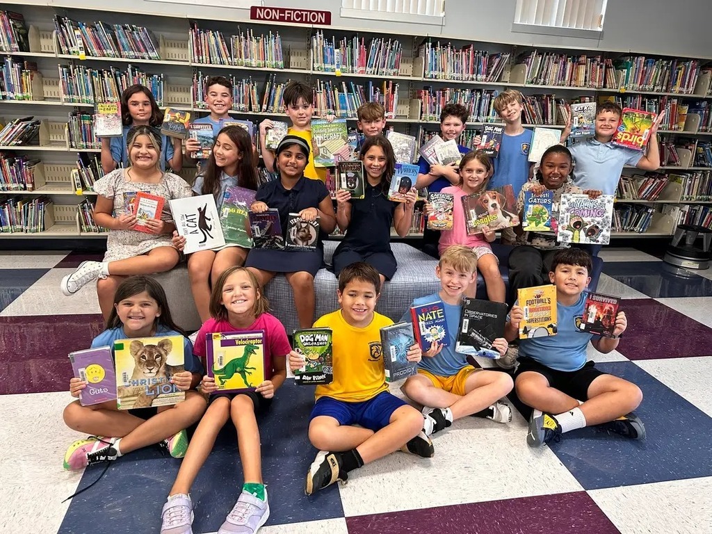 Class holding up the books they checked out of the library. 