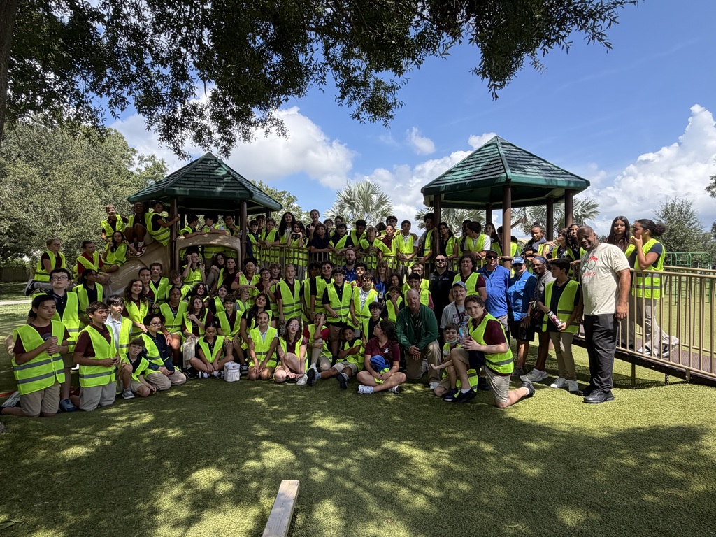 Group of students surrounding an outdoor playground and smiling 