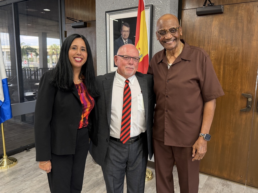 Board Members Nadia Combs and Henry "Shake" Washington smiling with Hillsborough Head Football Coach Earl Garcia Jr. 