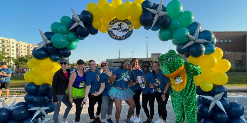 Race participants smiling balloon arch