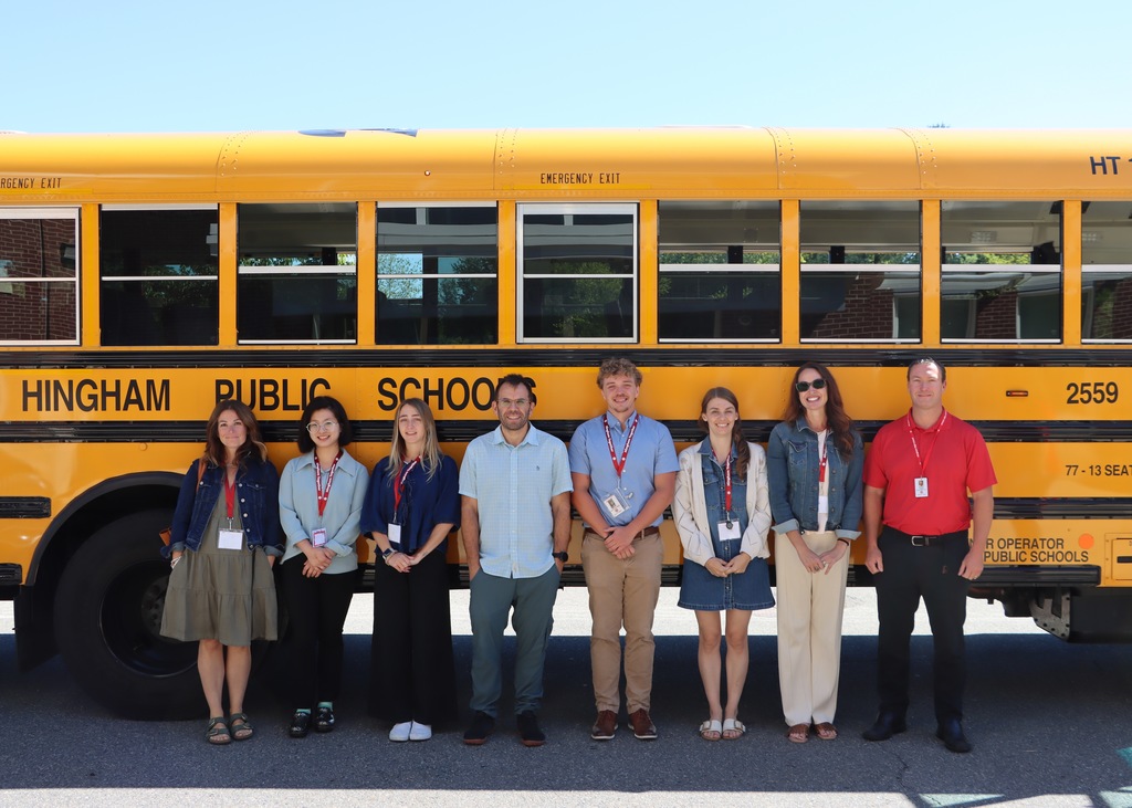 NEW TEACHERS STANDING IN FRONT OF HPS BUS SMILING.