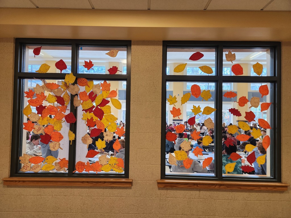 A colorful display of gratitude leaves in the colors of yellow orange and red scattered over cafeteria windows.