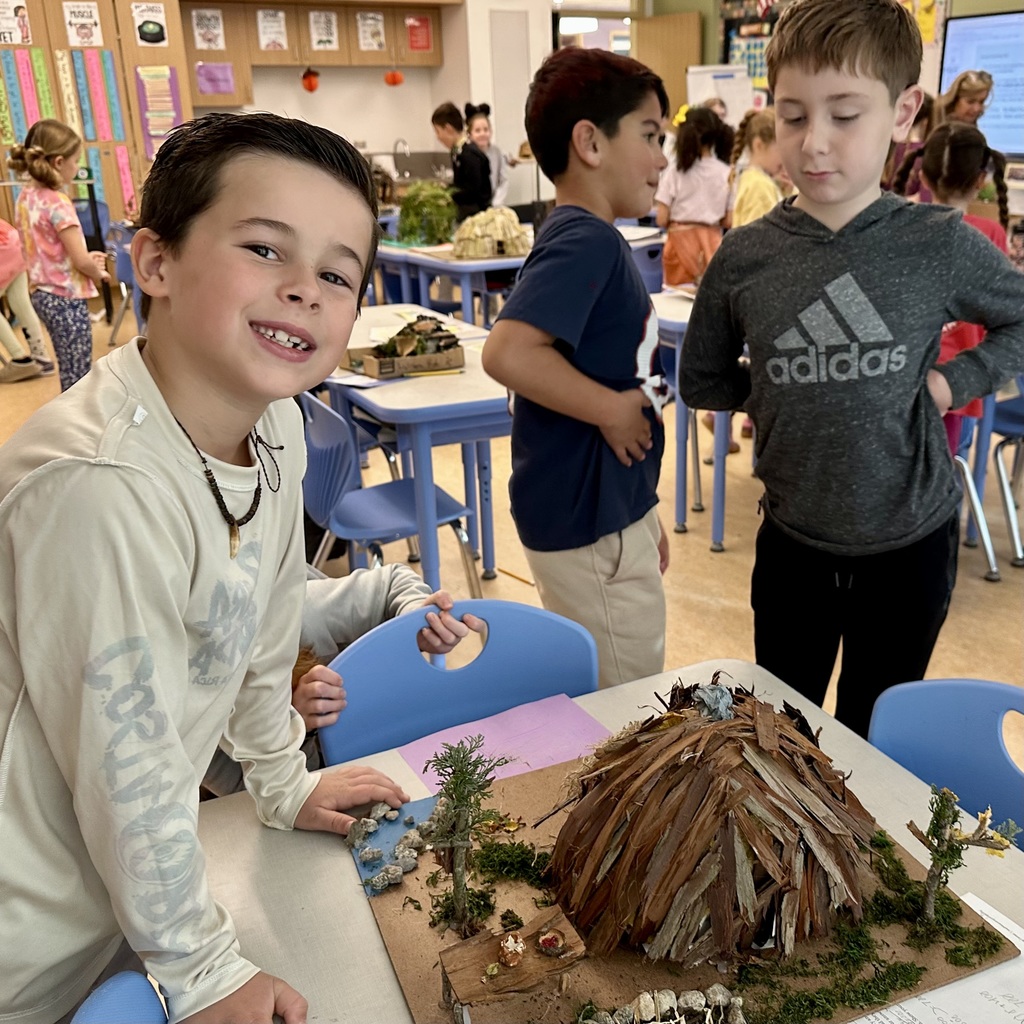 Student smiling at the camera showing off his wetu creation.