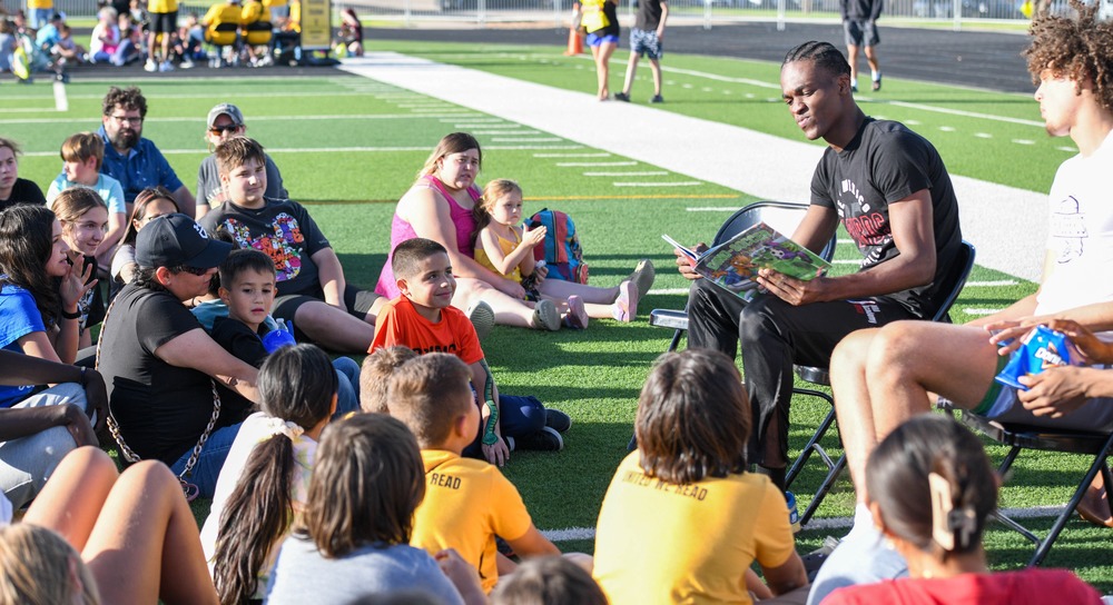 athelete reading to kids on field