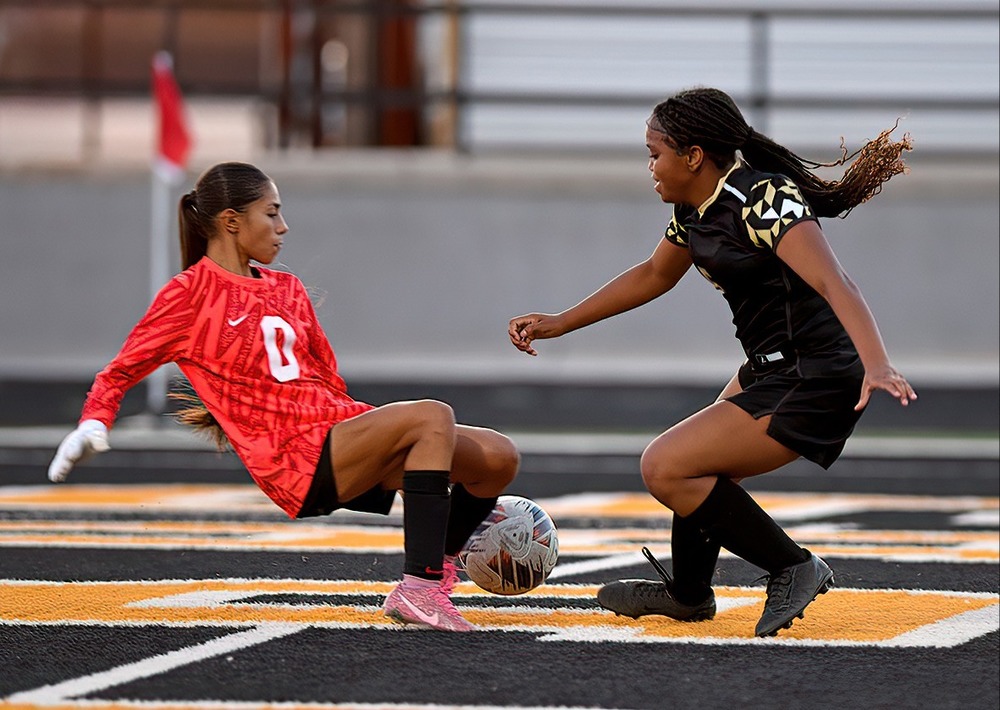 two girl soccer players going for ball