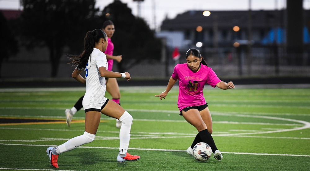 two girl soccer players going for ball