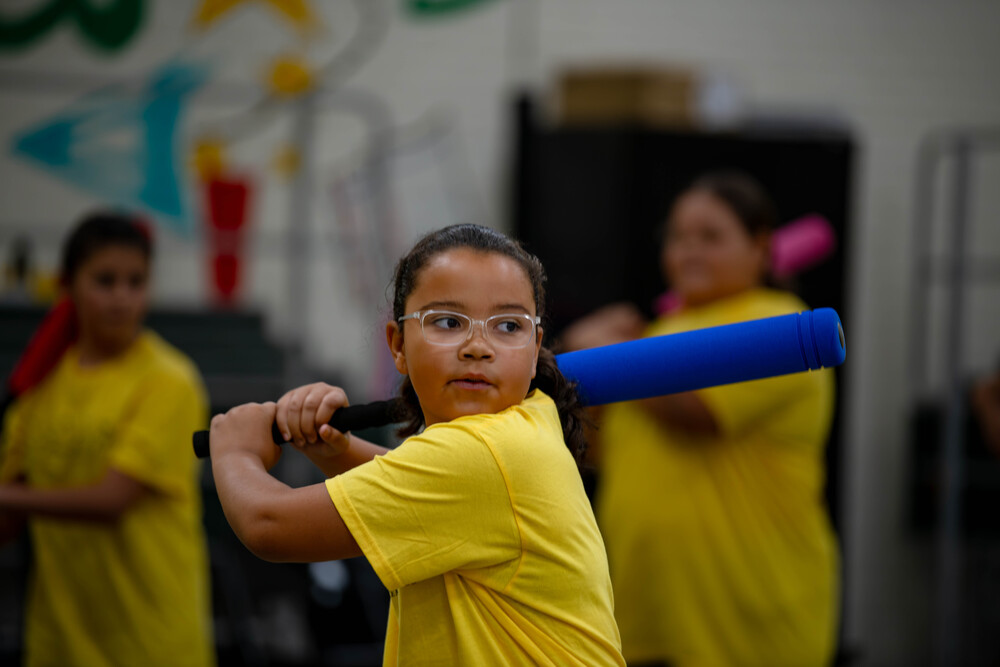 Child shown with a baseball bat, performing the choreography at the Studiio M Dance Residency