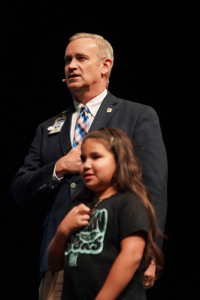 Superintendent, Gene Strickland performs Pledge of Allegiance with student on stage. 