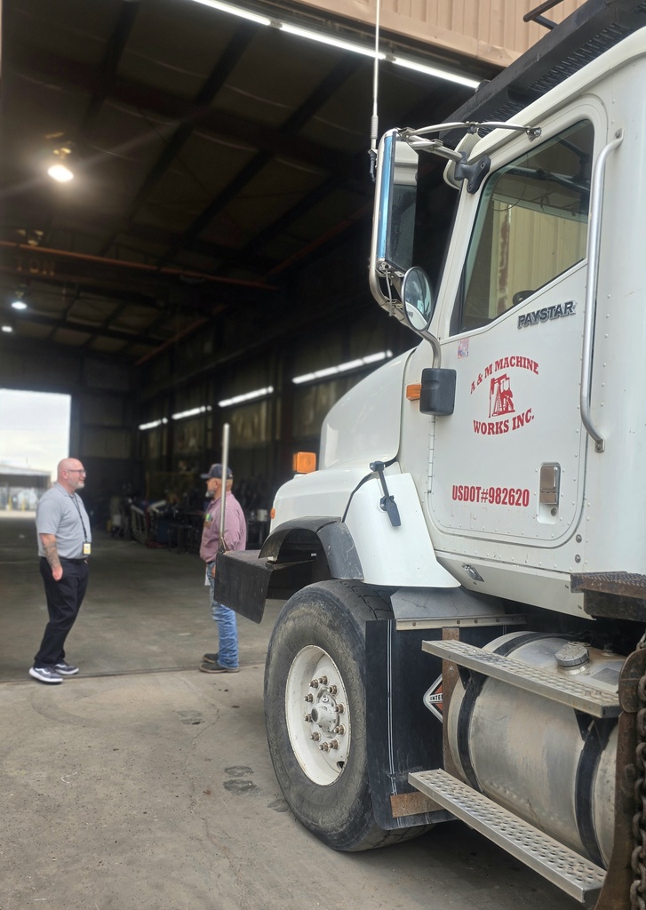 2 men standing near a semi-truck talking 