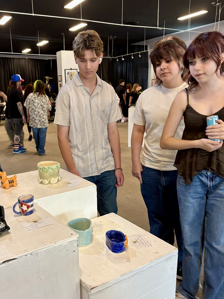 3 students looking at art