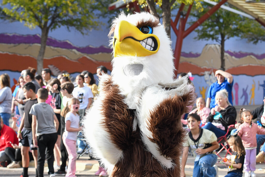 Hobbs Eagle Mascot shown walking the streets through the Homecoming parade, greeting children and passing out candy.