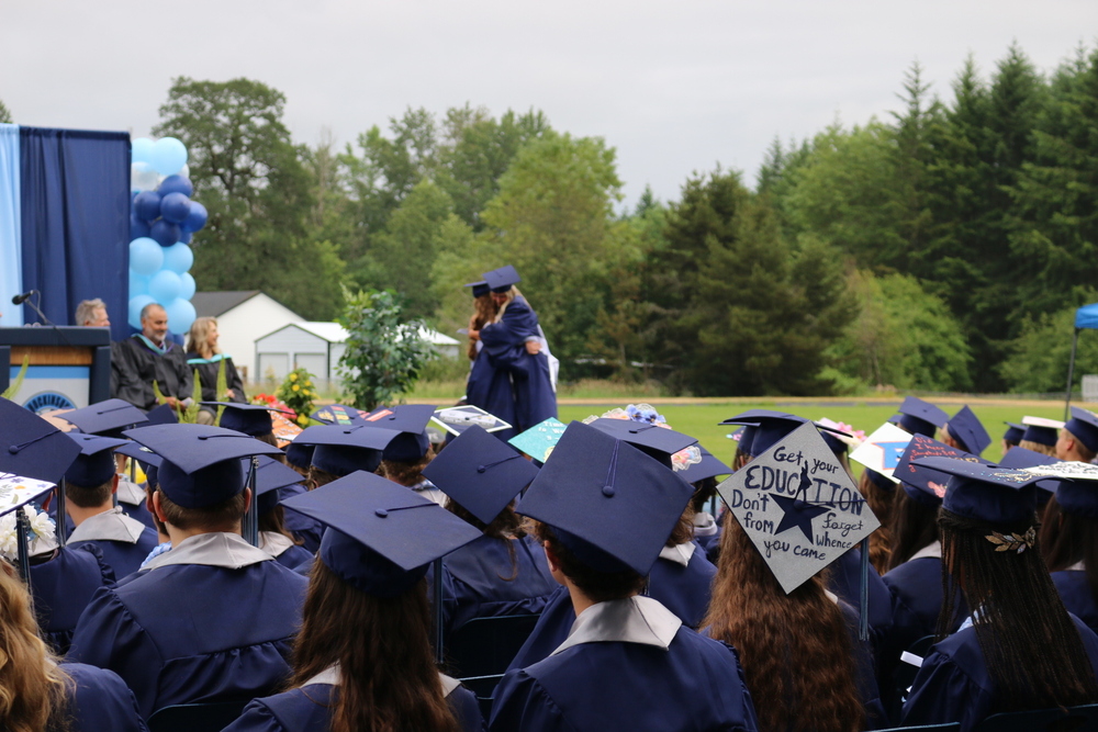 Hockinson High School Class of 2023 graduates sit wearing their caps and gowns at their graduation ceremony.