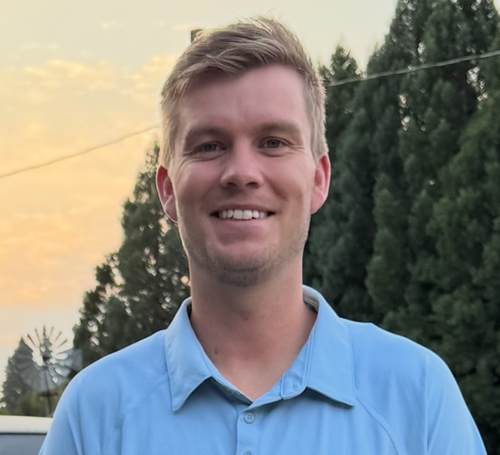 Man in light blue shirt poses for photo