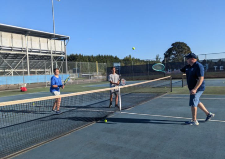 Boys Tennis Team players practice volleys at the net.