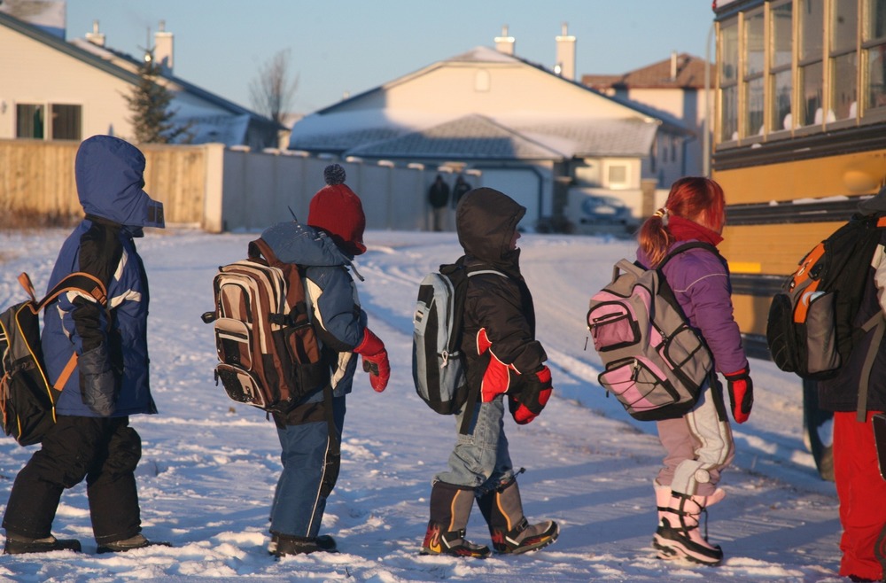 Students line up to get onto a school bus in snowy weather