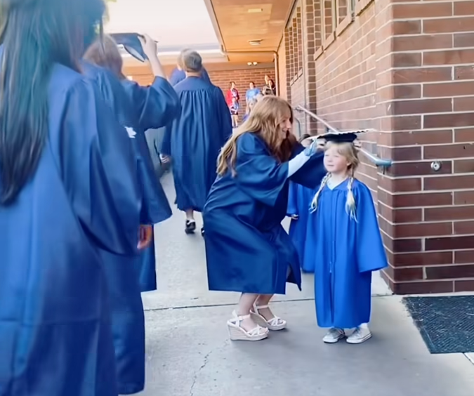 Screenshot of HHS student placing her cap on a Kindergarten student