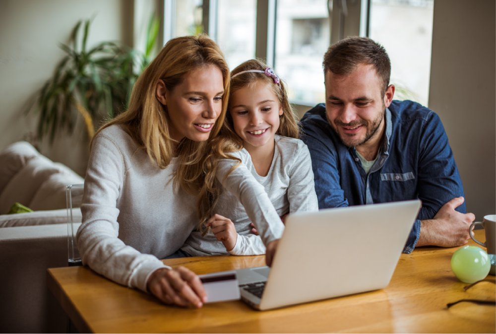 Mother, father and daughter look at laptop together.