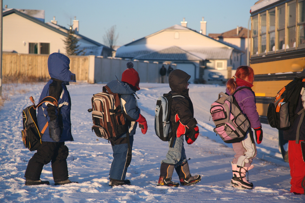 Students line up to enter a school bus in snowy weather.