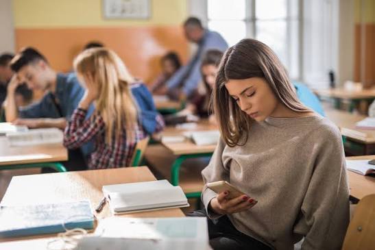 Stock image of student on cell phone in classroom