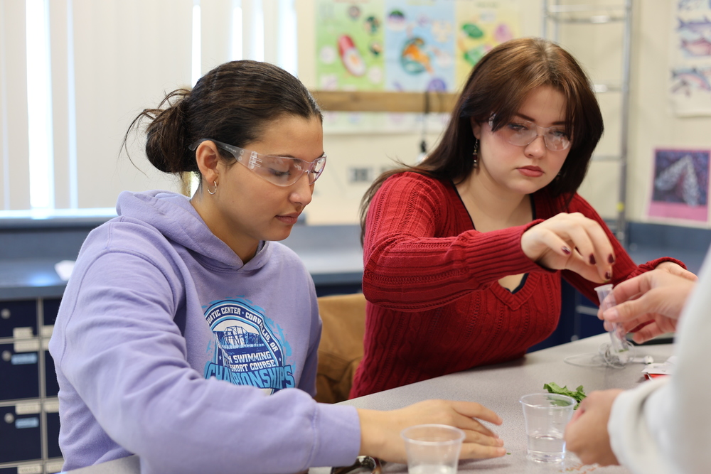 Two girls use science equipment in class