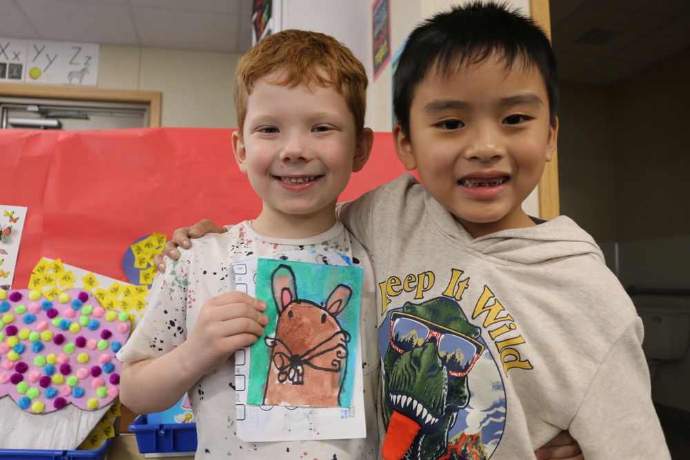 Two students hold a water color mouse painting.