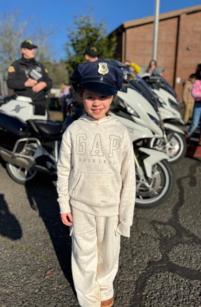 An HHES student smiles while wearing a police officer's cap at a 2026 PAL event.