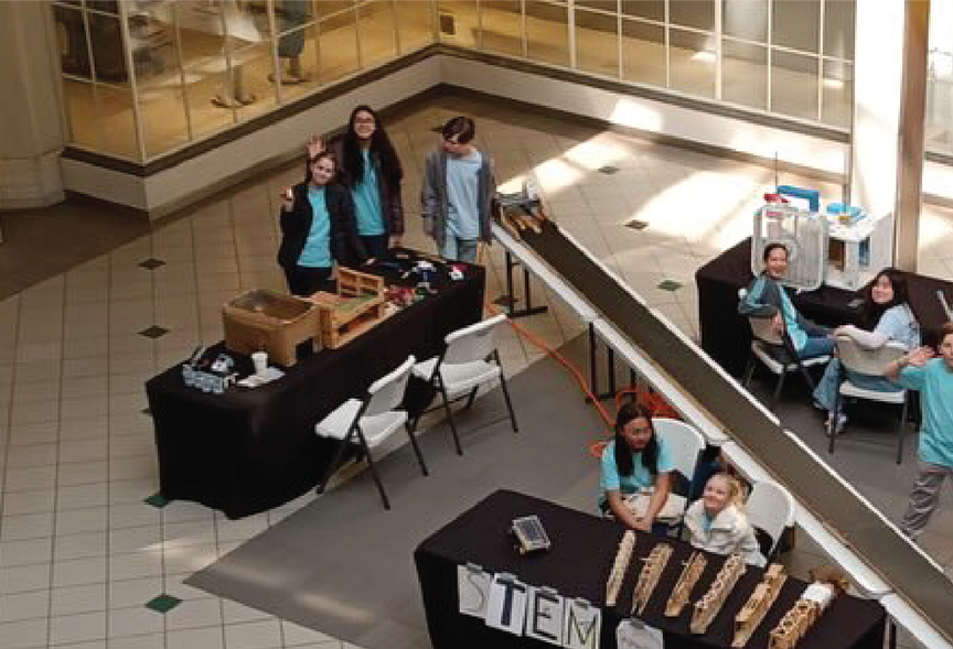 HMS stem ambassadors sitting at their booths and demonstrating their projects.