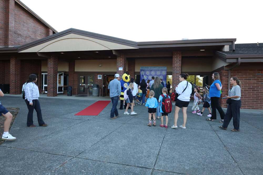 Group of students and parents in front of elementary school outdoors.